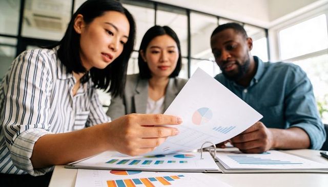 Collaborative team analyzing charts and reports on office table reviewing analytics