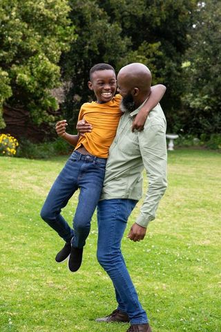 Father Lifting Son in Scenic Backyard for Quality Family Time