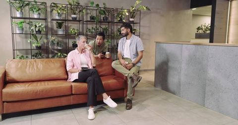 Diverse colleagues networking in modern office lounge with greenery