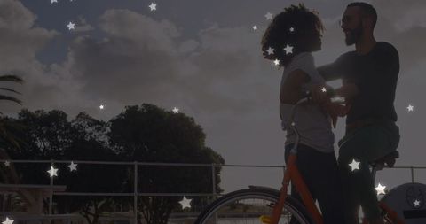Romantic Couple Enjoying Bike Ride by Waterside with Starry Overlay