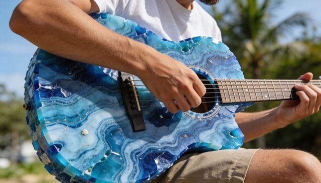 Playing acoustic guitar with blue agate resin body, sunlit outdoor music moment