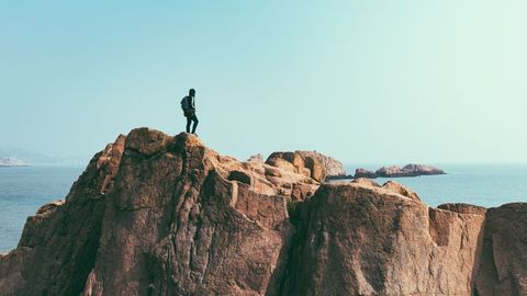 Adventurer Standing on Rugged Coastal Cliff Overlooking Sea