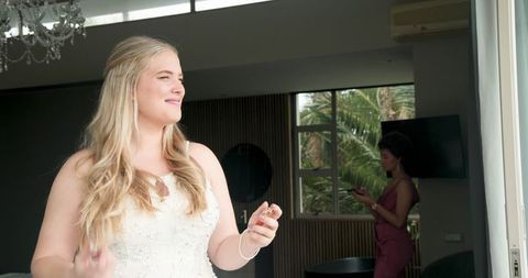 Joyful bride and supportive bridesmaid preparing for ceremony