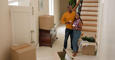 Couple embracing new home with cardboard boxes in hallway