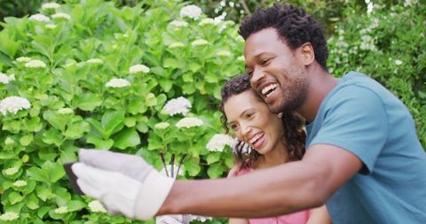 Smiling Biracial Couple Taking Selfie in Garden