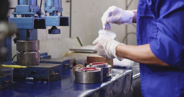 Technician mixing chemicals in industrial workshop, preparing materials for machinery. Suitable for use in articles related to industrial processes, manufacturing, chemical handling, and workshop safety.