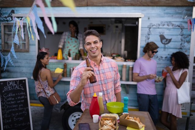 Smiling Man Holding Beer Bottle at Outdoor Food Truck - Download Free Stock Photos Pikwizard.com
