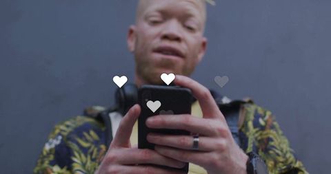 Man Engaged with Social Media on Smartphone Showing Floating Hearts