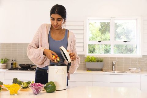 Asian Woman Composting Vegetables in Modern Kitchen