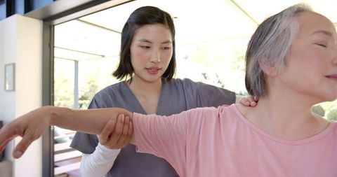 Physiotherapist guiding senior woman in home therapy session