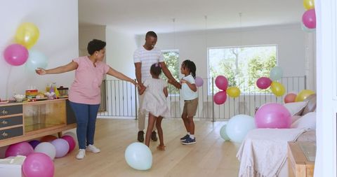 Joyful Family Dancing at Home Party with Colorful Balloons