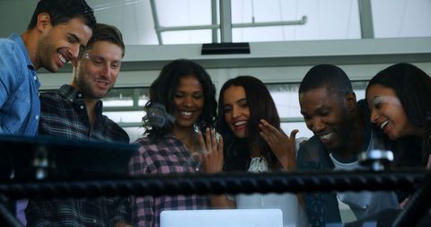 Diverse Team Collaborating Around Laptop with Focused Enthusiasm