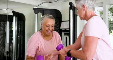 Cheerful Senior Women Exercising Together with Dumbbells at Home Gym