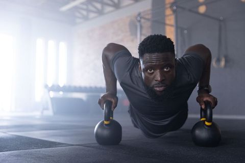Man performing kettlebell push-ups in industrial gym showing intense focus and strength