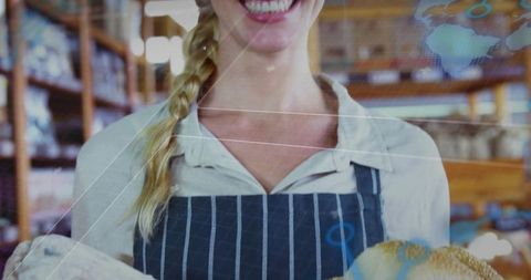 Smiling baker presenting freshly baked artisan bread in rustic bakery interior