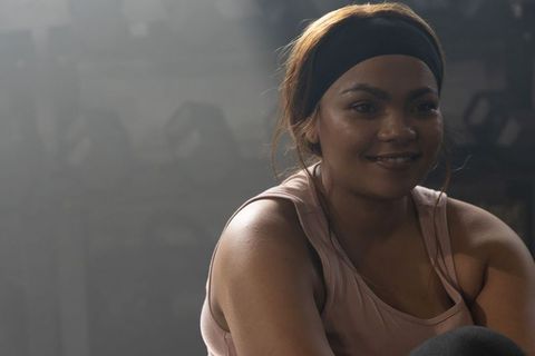 African american woman resting after intense workout in dim hazy gym wearing headband
