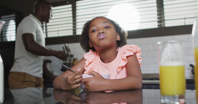 Young girl enjoying breakfast in kitchen with father cooking - Download Free Stock Images Pikwizard.com