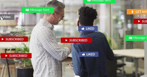 Man pointing at tablet explaining social media badges to colleague in modern office