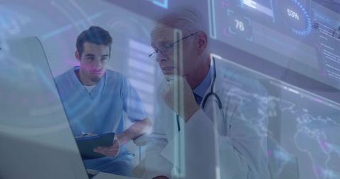 Senior physician consulting with medical trainee while reviewing digital medical dashboard