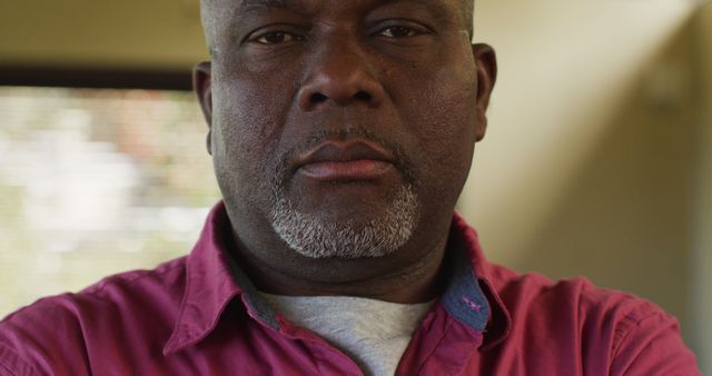 Close up portrait of thoughtful african american senior man looking straight to camera. retirement lifestyle, spending time alone at home.