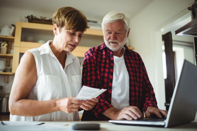 Senior couple using laptop for online banking and paying bills. Ideal for illustrations of elderly finance management, online banking services, financial planning for retirees, and modern technology use by older adults.