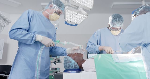 Diverse male and female surgeons with face masks during surgery with african american female patient. Medicine, healthcare and hospital, unaltered.