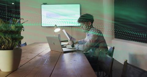 Man reviewing documents and working on laptop in modern conference room