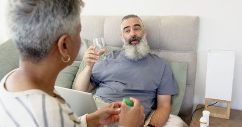 Caregiver Providing Medicine to Relaxed Patient at Home