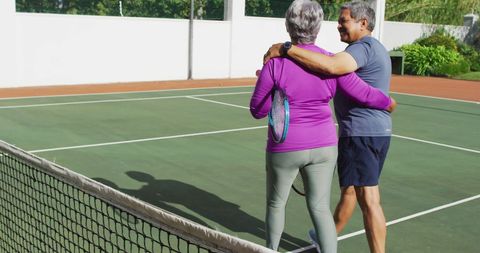 Happy senior couple embracing on tennis court