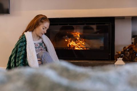 Red-Haired Woman Relaxing by Fireplace in Cozy Living Room