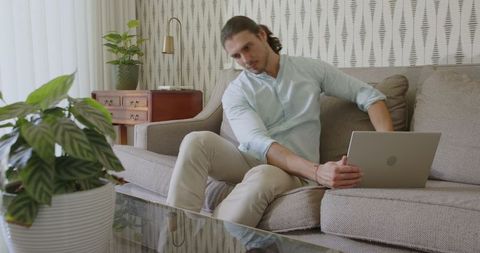 Focused Man Working Remotely on Sofa With Laptop