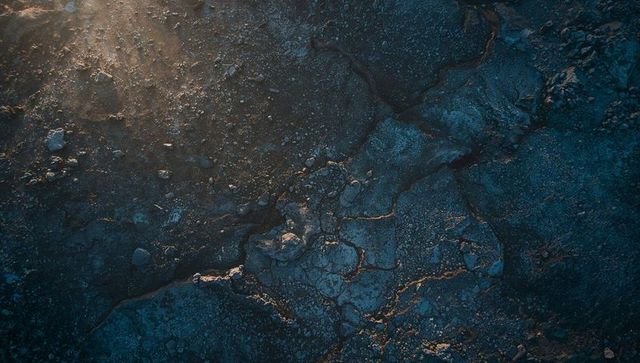 Aerial revealing cracked bedrock and fissures across barren plain at golden hour