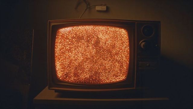 Vintage CRT Television Displaying Orange Static in Dimly Lit Den