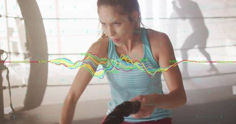 Focused athlete training with battle ropes in gym