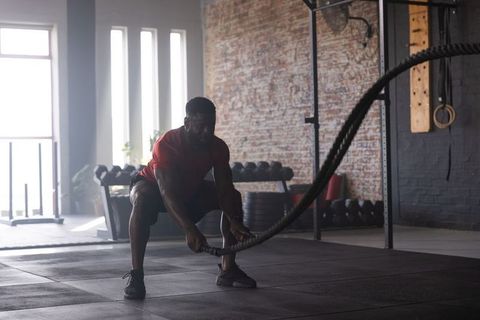 Swinging heavy battle ropes while holding low squat for power and endurance training
