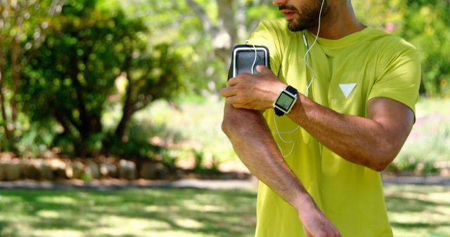 Young Man Adjusting Smartphone Armband While Jogging in Park - Download Free Stock Photos Pikwizard.com