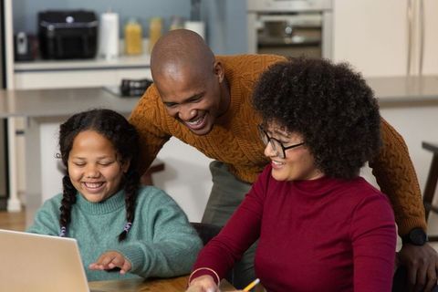 Smiling family learning together using laptop for homeschooling and online education