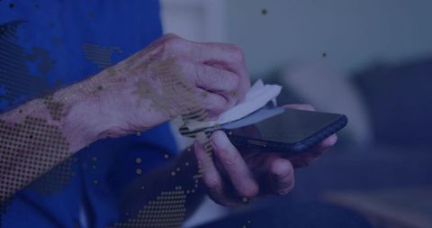 Senior man cleaning smartphone with disinfecting wipe showing wrinkled hands and age spots