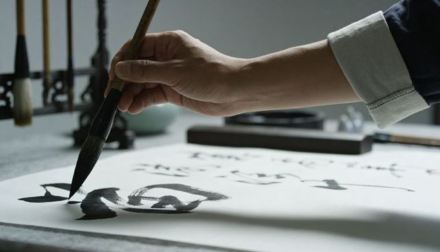 Hand painting traditional east asian calligraphy with ink brush on rice paper