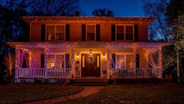 Charming two-story home brightly lit with festive string lights