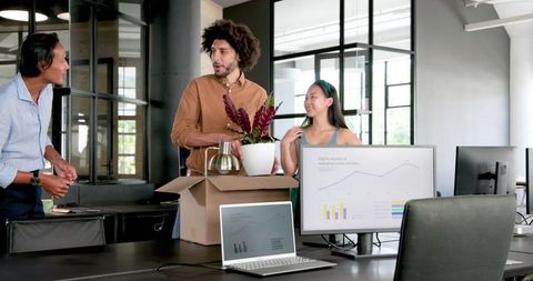 Colleagues unpacking office items in modern workspace