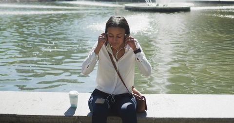 Woman enjoying music by tranquil pond