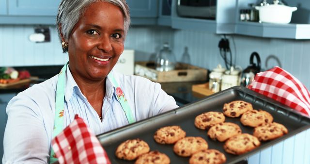 Smiling Woman Holding Freshly Baked Chocolate Chip Cookies in Kitchen - Download Free Stock Images Pikwizard.com