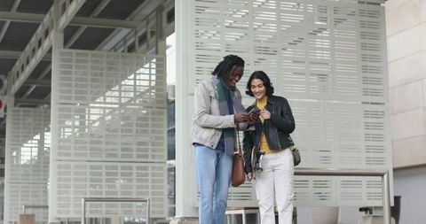 African american man and woman checking smartphone at modern transit platform with camera