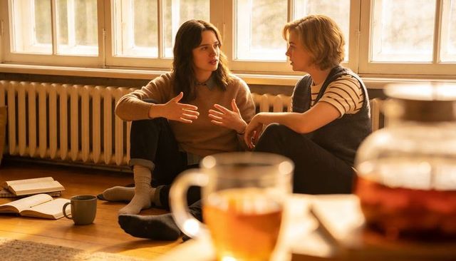 Cozy sunlit living room conversation between friends sharing tea and books