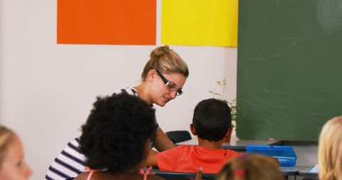 Teacher Assisting Young Students in Colorful Classroom Environment