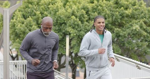 Young and mature men running up outdoor stairs for urban fitness training and health