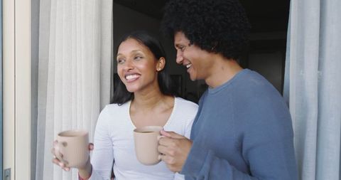Diverse Couple Enjoying Morning Coffee by Sliding Door in Warm Light