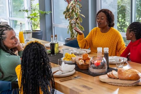 Multigenerational african american family at sunlit dining table sharing bread