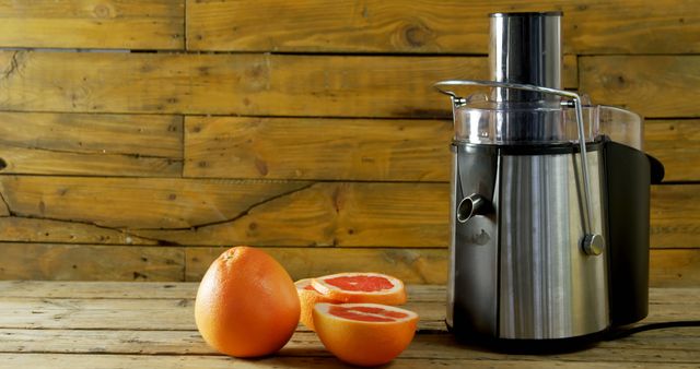 Juicing fresh grapefruit using modern juicer on wooden table indoors. Ideal for websites, magazine articles, blog posts related to healthy lifestyle, fresh beverages, kitchen appliances, breakfast ideas, and food preparation tutorials.